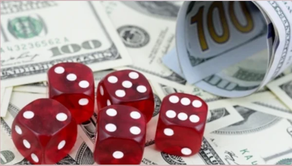 Five red Yahtzee dice on top of hundreds of dollars in cash